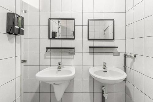 a white tiled bathroom with two sinks and mirrors at Jiufen Nostalgic Inn in Jiufen