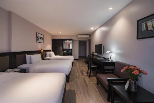a hotel room with three beds and a desk at La Passion Classic Hotel in Hanoi
