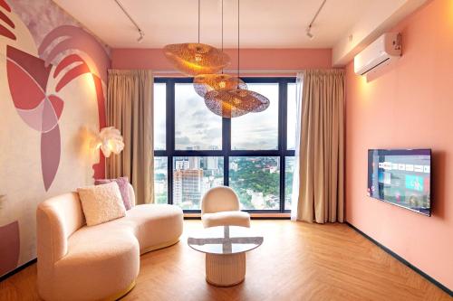 a living room with a couch and a chair and a chandelier at Urban Suites, Signature Collection by Stellar ALV in Jelutong