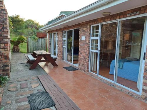 a patio with a bench and a table in front of a building at Cove Rock Lodge on Cowrie in East London