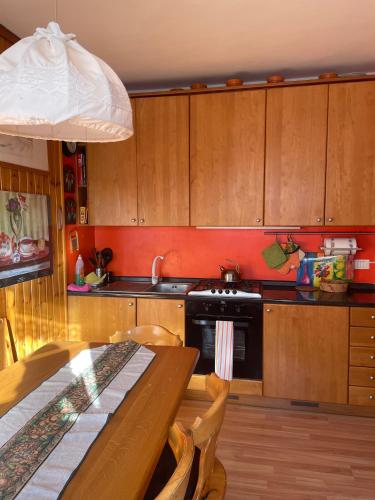 a kitchen with wooden cabinets and a table and a stove at Delizioso appartmento tra le Alpi in Prali Villa