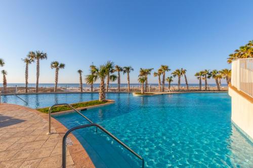 a swimming pool with palm trees and a beach at Turquoise Place Condos in Orange Beach