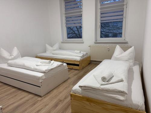 two beds in a room with two windows at Gemütliche Wohnung direkt am Bahnhof perfekte Lage in Bitterfeld