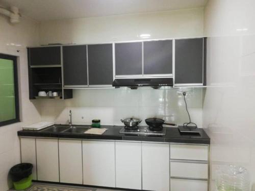 a kitchen with white cabinets and a black counter top at Vista Alam 3 bedroom in Shah Alam
