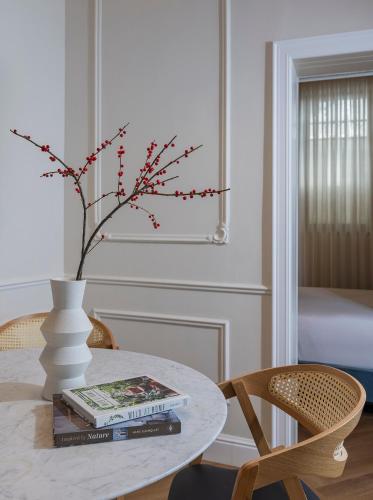 a dining room table with a vase and books on it at Villa Albi - Machne Yehuda Hotel in Jerusalem