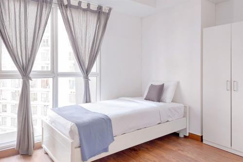 une chambre blanche avec un lit et une grande fenêtre dans l'établissement Cozy Living 2BR Apartment at Casa de Parco By Travelio, à Tangerang