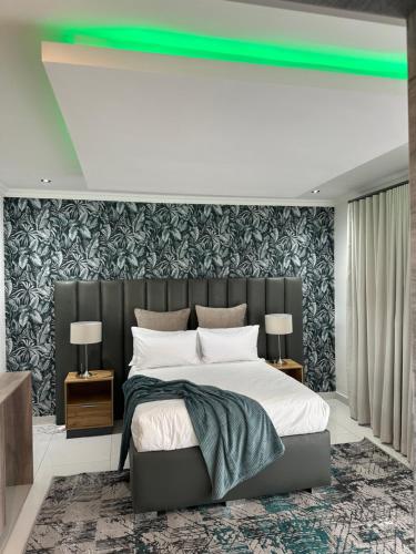 una camera da letto con un grande letto con una luce verde sopra di esso di Nouvelle Ere Beauty Spa & Boutique Guesthouse a Centurion