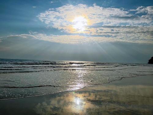 a beach with the sun shining on the water at Thungwua laen resort in Chumphon