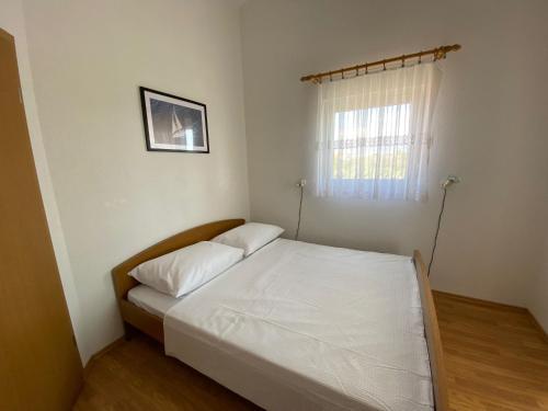 a bedroom with a bed with white sheets and a window at Apartman Palma in Vir