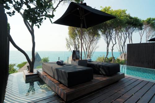 a patio with a couch and an umbrella next to a pool at Silavadee Pool Spa Resort - SHA Extra Plus in Lamai