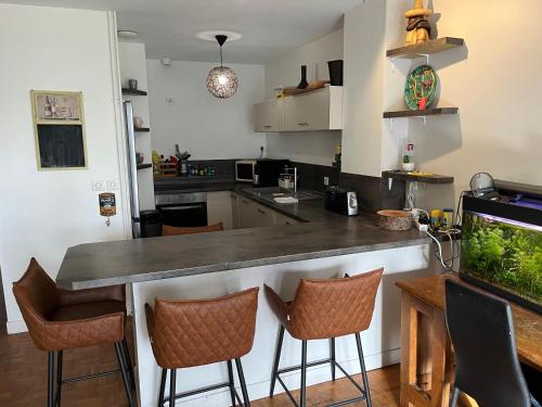 a kitchen with a bar with stools and a fish tank at Appartements Caen Centre in Caen