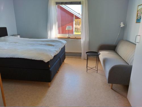 a bedroom with a bed and a couch and a window at STF Orsa Hostel in Orsa