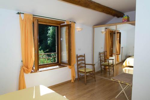 Cette chambre comprend une fenêtre, 2 chaises et un lit. dans l'établissement Gîte Gîte Le Baptistou - 7/9 personnes, à Fraissinet-de-Fourques