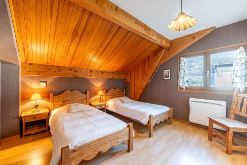 a bedroom with two beds and a wooden ceiling at chalet pierre et bois in Aigueblanche