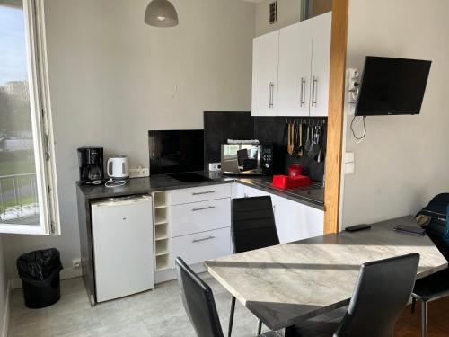 a kitchen with white cabinets and a table with chairs at Appartements Caen Centre in Caen