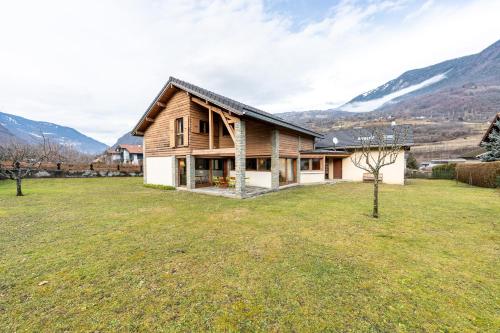 a house in a field with mountains in the background at chalet pierre et bois in Aigueblanche