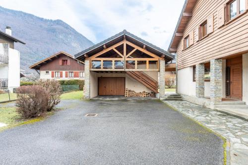 a house with a garage with a mountain in the background at chalet pierre et bois in Aigueblanche