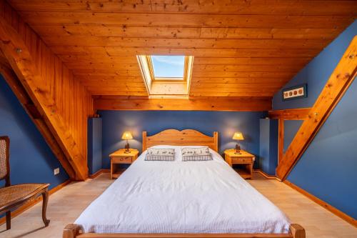 a bedroom with a large bed with blue walls and wooden ceilings at chalet pierre et bois in Aigueblanche