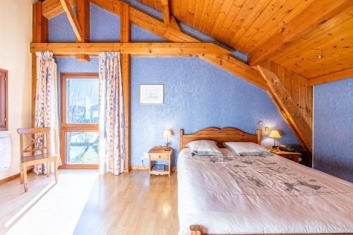 a bedroom with a large bed and a wooden ceiling at chalet pierre et bois in Aigueblanche