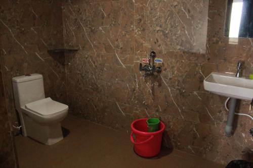a bathroom with a toilet and a sink and a bucket at Golden IB'S Gokarna in Gokarna