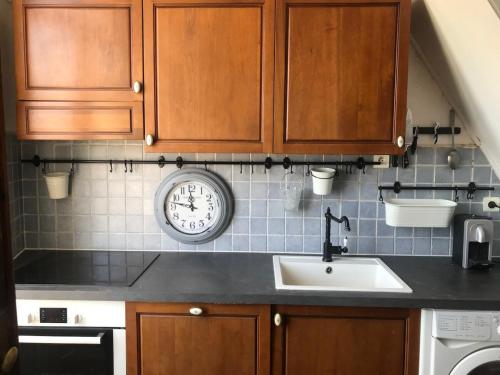 une cuisine avec un évier et une horloge murale dans l'établissement La Tour Morazzani Cap Corse Hideaway, à Brando