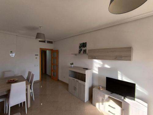 a living room with a television and a dining table at APARTAMENTO TURISTICO 2ºD CARLOS III - Cerca de la playa in Roquetas de Mar