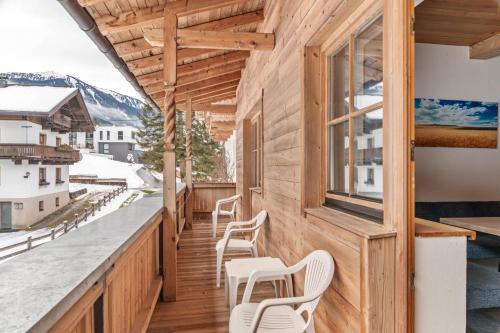 balcón de madera con sillas blancas y ventana en Schwüwong - Apartment 12, en Kelchsau