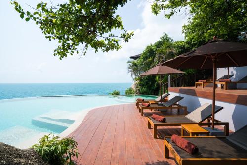 a pool with chairs and umbrellas next to the ocean at Silavadee Pool Spa Resort - SHA Extra Plus in Lamai