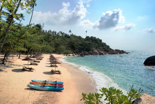 a beach with chairs and umbrellas and a row of boats at Silavadee Pool Spa Resort - SHA Extra Plus in Lamai