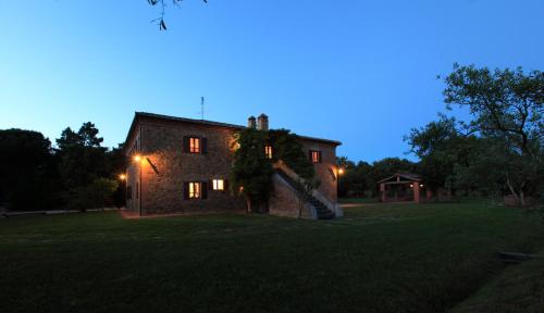 an old stone house at night with lights at Podere Marella in I Pieracci