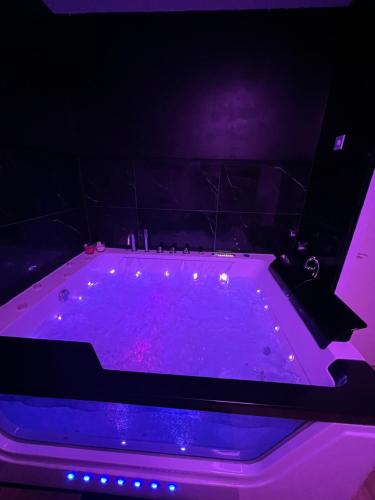 a purple bath tub with lights in a room at L’escapade Paris spa in Vauréal