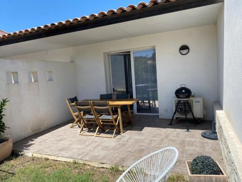 un patio avec une table et des chaises sur un patio dans l'établissement Villa résidence avec piscine chauffée Bonifacio, à Bonifacio