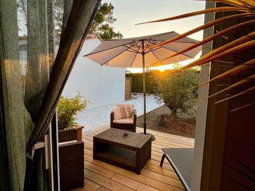 une terrasse avec un parasol, une chaise et une table dans l'établissement Sun Oasis Suite Parentale, à Bretignolles-sur-Mer