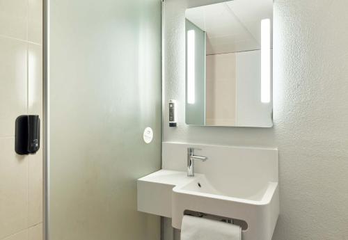 a white bathroom with a sink and a mirror at B&B HOTEL Orly Rungis Aéroport 2 étoiles in Rungis