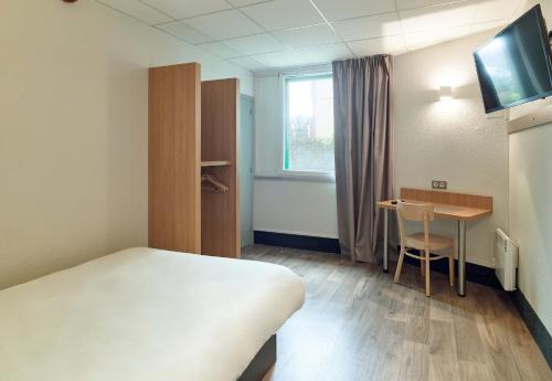 a room with a bed and a desk and a table at B&B HOTEL Orly Rungis Aéroport 2 étoiles in Rungis