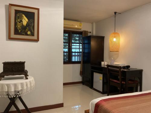ein Schlafzimmer mit einem Bett, einem Tisch und einem Stuhl in der Unterkunft Baan Klang Vieng in Chiang Mai