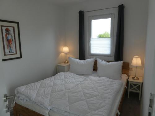 a bedroom with a bed with white sheets and a window at Mobilheim Schleistern und Schleisonne in Kappeln