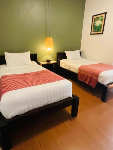 two beds in a room with green walls at Baan Klang Vieng in Chiang Mai