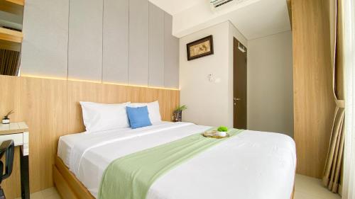 ein Schlafzimmer mit einem großen weißen Bett mit blauen Kissen in der Unterkunft Homey and Good Place 2BR Transpark Bintaro Apartment By Travelio in Tangerang
