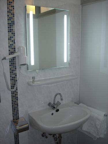 a white bathroom with a sink and a mirror at Rhein-Hotel in Andernach