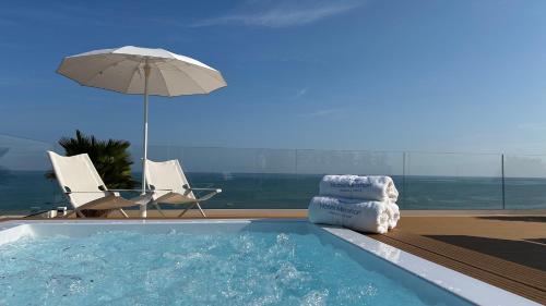 a swimming pool with an umbrella and a chair and an umbrella at Hotel Mirafiori in Lido di Jesolo