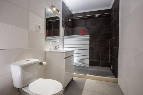 La salle de bains blanche est pourvue d'une douche et de toilettes. dans l'établissement Alex Surf Hostel, à Baleal