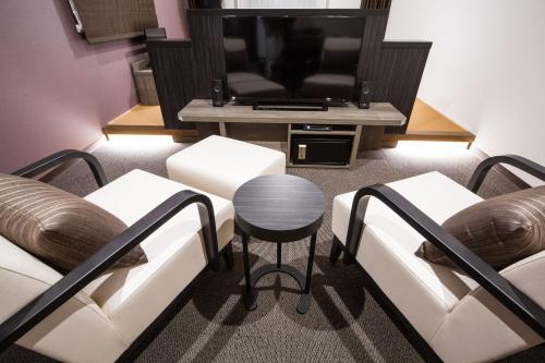 a living room with two white couches and a television at HOTEL MYSTAYS PREMIER Kanazawa in Kanazawa