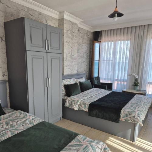 a bedroom with two beds and a large cabinet at Pembe Köşk Otel in Akcay