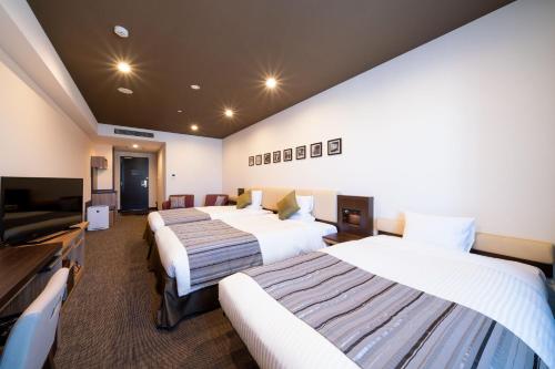 a hotel room with two beds and a flat screen tv at HOTEL MYSTAYS PREMIER Kanazawa in Kanazawa