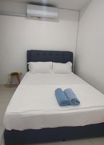 a white bed with two blue pillows on it at Ayesha Metrocity Staycation N-02 & N-5-03 in Kuching