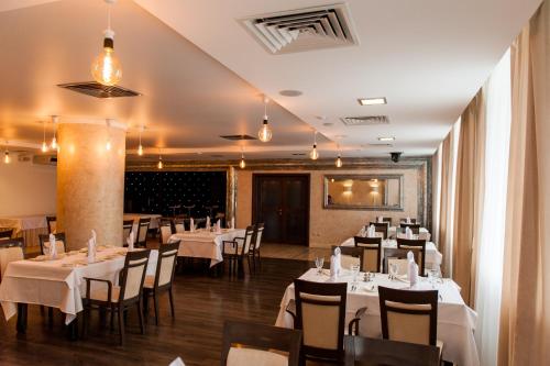 a dining room with white tables and chairs at Avrora Business Hotel in Kursk