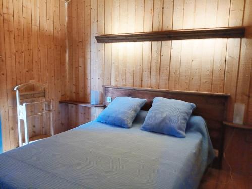 a bedroom with a bed with two blue pillows at Le Séchoir Aquitain, logement insolite in Dolmayrac