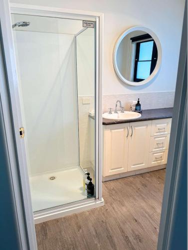a shower in a bathroom with a sink and a mirror at Banksia in Port Campbell