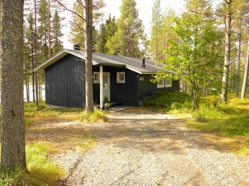 una baita nera nel bosco con un vialetto di ghiaia di Lomakylä Atimo ad Alakitka